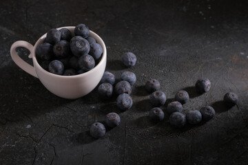 White cup with blueberries on a black background. High quality photo