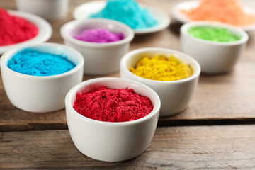 Obraz na płótnie Canvas Colorful powder dyes on wooden background, closeup. Holi festival