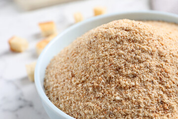 Fresh breadcrumbs in bowl on white marble table, closeup