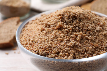 Fresh breadcrumbs in bowl on white wooden table, closeup