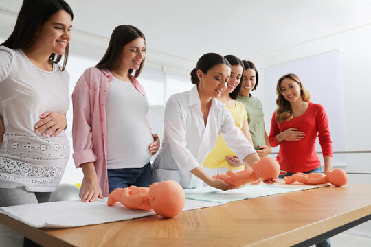 Pregnant Women Learning How To Swaddle Baby At Courses For Expectant Mothers Indoors