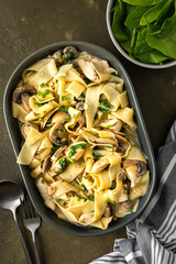 Fettuccini pasta with mushrooms and chicken breast and basil in a creamy sauce, top view