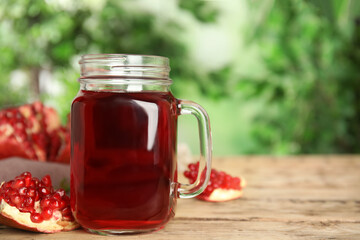 Pomegranate juice in mason jar and fresh fruits on wooden table outdoors, space for text