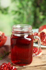 Pomegranate juice in mason jar and fresh fruits on wooden table outdoors