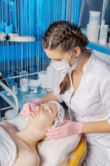 Professional beautician wipes a woman's face after the procedure.