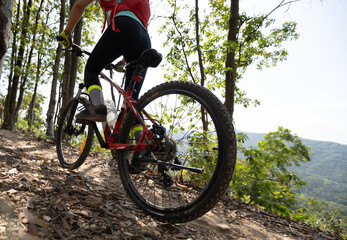Fototapeta na wymiar Woman cyclist cycling on mountain top forest trail