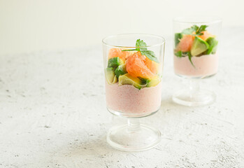 Two glasses with appetizer of tarama or taramasalata with avocado and pink grapefruit on the light gray background close-up with copy space