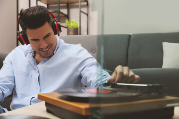Happy man listening to music with turntable at home