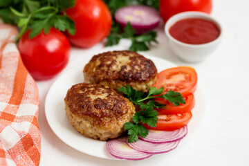 Homemade cutlets with tomatoes, onions, on a white plate.