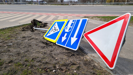 Damaged Broken Traffic Signs With Bus Direction Arrow and Pedestrian Crossing Road are Laying on the ground on a Street.