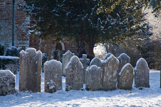 a row of old gravestones covered in snow in a churchyard