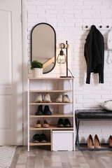 Obraz na płótnie Canvas Shelving unit with shoes and different accessories near white brick wall in hall. Storage idea