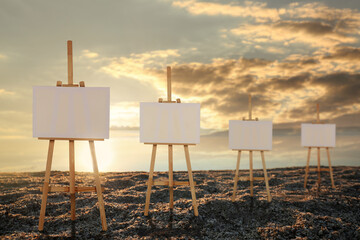 Wooden easels with blank canvases on beach near sea at sunrise