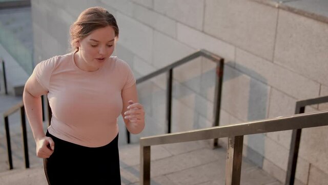 Positive sportswoman climbing stairs outdoors, cardio training, body endurance