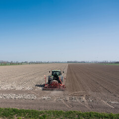Obraz premium farmer works his land on rural countryside of noord beveland in dutch province zeeland on sunny spring day