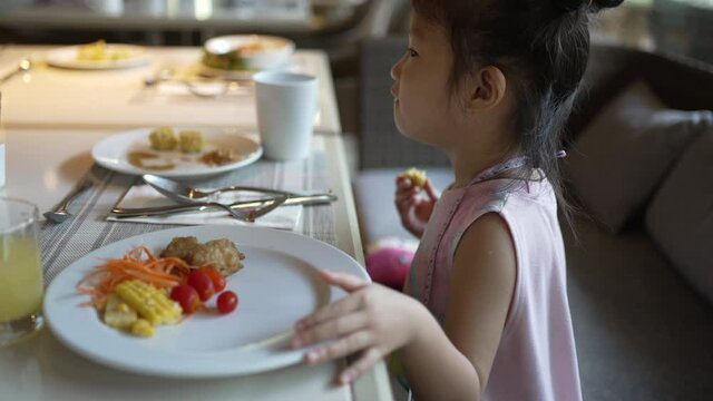 Asian girl eating egg omelet with vegetable, tomato, cheese and herb in hotel restaurant in morning 