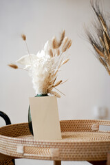 Summer stationery still life. Closeup of blank card mock-up with dry leaf in boho interior. Grunge beige concrete background. Flat lay. Moody boho design