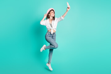 Fototapeta na wymiar Photo of sweet cute young woman dressed white shirt cap tacking selfie modern device jumping isolated teal color background