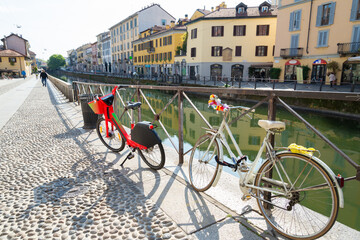 Bicycles in the famous Navigli neighborhood, Milan, Italy. Water canal looks like a river. Buildings and sky in the background.