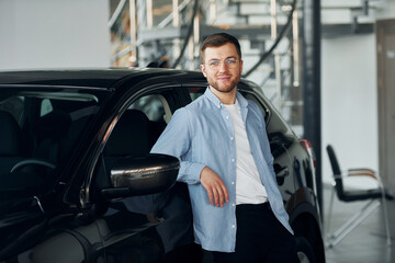Plakat Successful man in glasses standing near brand new car indoors