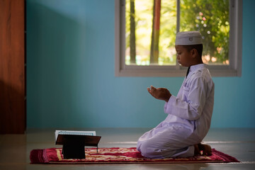 The boy is praying and learning to recite the Quran from the mosque, a concept of the next generation of Islam.