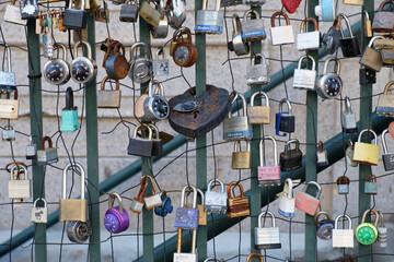 Padlocks attached to a wire fence and metal railing to express love for another person
