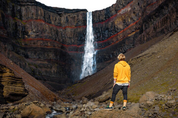 Tourist looking at the Hengifoss waterfall in Iceland