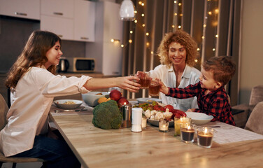 Spending weekend together. Happy family of mother, daughter and son is on the kitchen at evening time