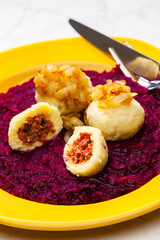 potato dumplings filled with smoked meat with fried onion on red cabbage