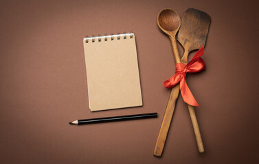 old spoon and spatula tied with red ribbon on a brown background, top view, copy space