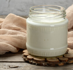 homemade yogurt in a glass transparent jar on a wooden table