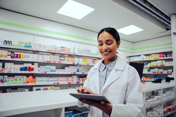 Portrait of smiling african doctor woman working in drugstore with digital tablet