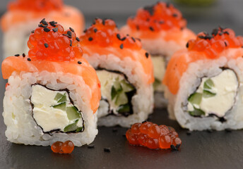 Philadelphia sushi with red caviar on a black slate board