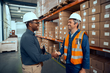Multiracial engineers shaking hands with each others at manufacturing industry
