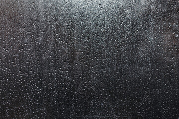 Bright raindrops on a window glass and dark background  - 427918723