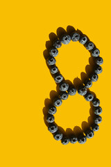 Healthy food, raw food, breakfast. Blueberries in the shape of a figure eight on a yellow background.