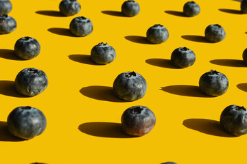 Healthy food, raw food, breakfast. Blueberries in hard harsh light against a bright yellow background. Patern.