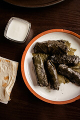Georgian dish dolma. minced meat in grape leaves on a clay plate with white sauce