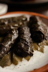 Georgian dish dolma. minced meat in grape leaves on a clay plate with white sauce