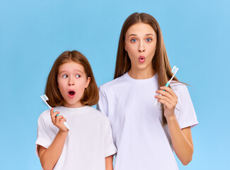 Astonished mother and girl brushing teeth