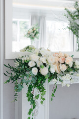 A large, tall arrangement of artificial flowers in white and peach on an empty table with a blue...