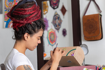 woman sitting with dreadlocks making handcrafts at home