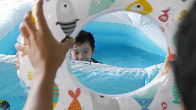 4K Asian Cute Child Boy Laughing, Playing Ball In Water In Pool At Home With Relaxing Face With Father. Concept Of Family Activity At Home, Freedom Fun, Songkran Festival 2021, New Normal Covid 19.