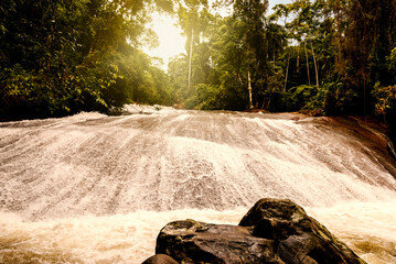 Tobogan waterfall illuminated by the sun's rays. Tourist spot in the mountains near the city of Paraty, Brazil.