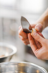 The male chef cleans and cuts the garlic with a knife on a wooden cutting board close-up.