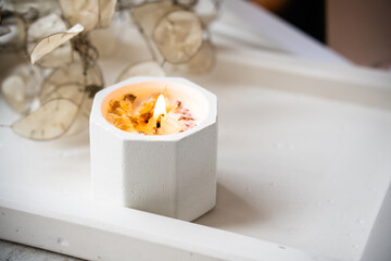 Home decoration with burning aromatic candle, white interior decor