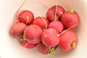 Organic ripe, light red radish on a white plate, close-up.