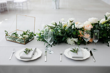 serving on the table of the newlyweds. White plate with glasses and utensils on the background of a blue tablecloth