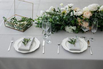 serving on the table of the newlyweds. White plate with glasses and utensils on the background of a blue tablecloth