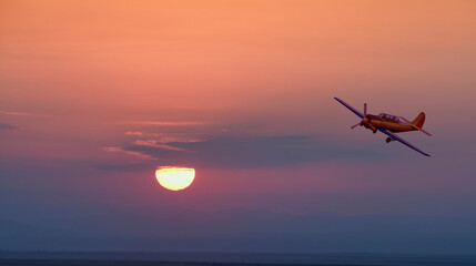 Beautiful colorful sunset landscape and vintage light propeller plane flying